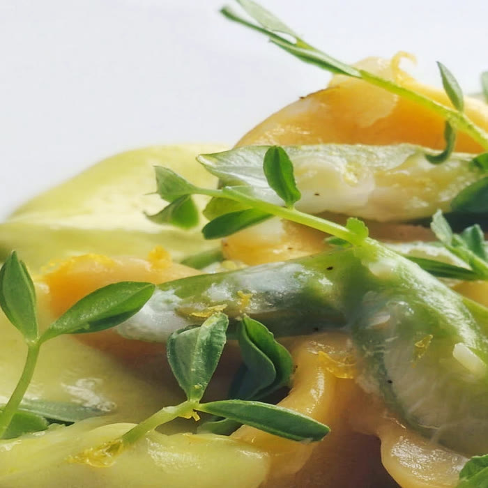 Pea shoots and lemon zest on saffron-herb sauce