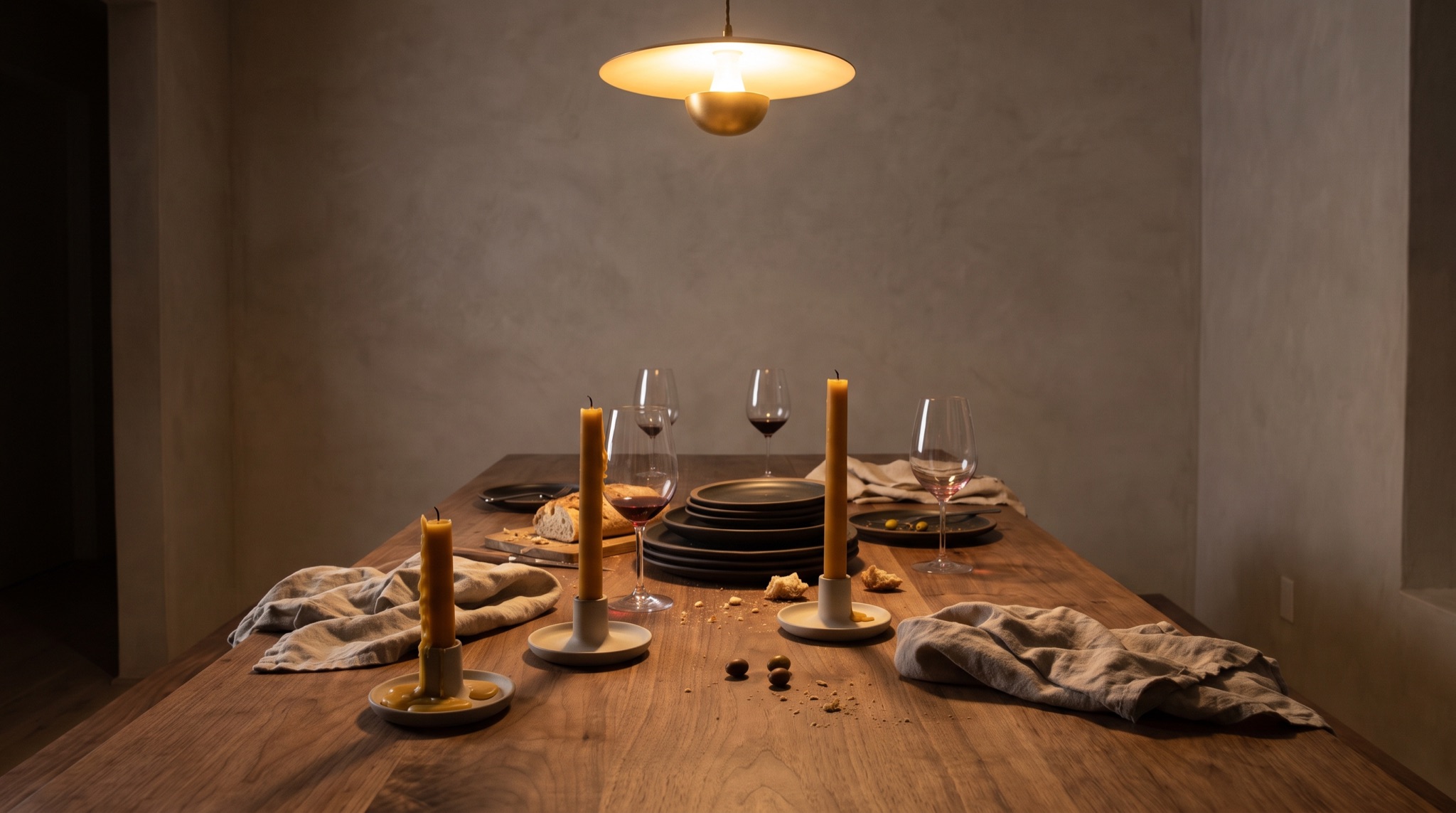 A long dining table set for eight by candlelight, cream linen and amber glassware